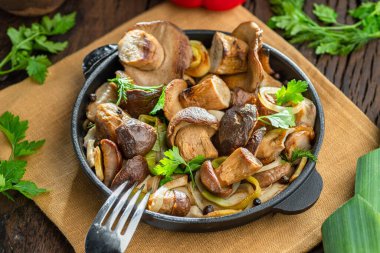 Ahşap masadaki kızartma tavasında domuz mantarı pişirdim. Üst görünüm.