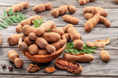 Olgun demirhindi meyvesi, yapraklar ve ahşap masada biraz demirhindi tohumu..