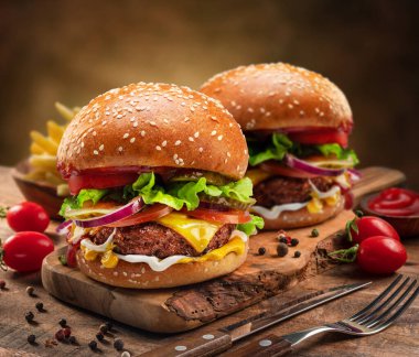 Tahta tepside lezzetli çizburgerler ya da hamburgerler, yanında biraz baharat ve çatal bıçak takımı..