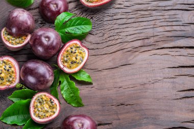 Dark purple passion fruits and it's half with seedly interior on wooden table. 