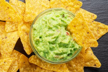 Guacamole sosu ve tortilla cipsi, popüler Meksika yemekleri servis tahtasında. Üst görünüm.