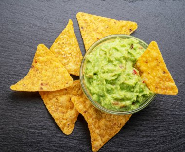 Guacamole sosu ve tortilla cipsi, popüler Meksika yemekleri servis tahtasında. Üst görünüm.