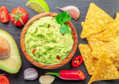 Guacamole sosu ve guacamole malzemeleri, popüler Meksika yemekleri servis tahtasında. Üst görünüm.