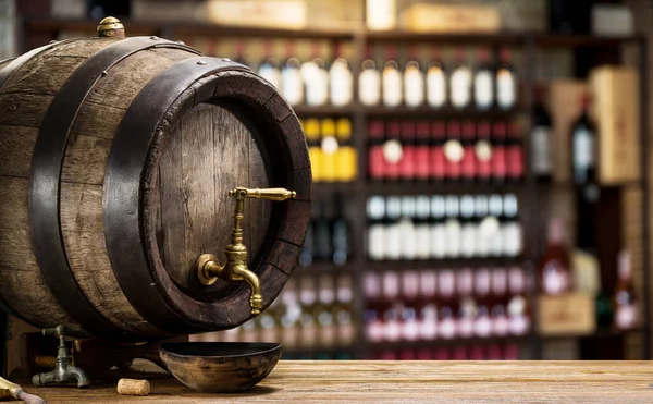 Wine barrel with copper tap and bottles of wine on the shelves at the background.