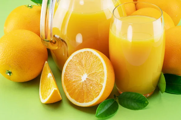Gelbe Orangenfrüchte Und Frischer Orangensaft Isoliert Auf Grünem Hintergrund Nahaufnahme — Stockfoto