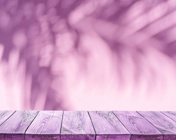 前景にはピンク色の壁に熱帯のヤシの葉と古い板張りのテーブルの上に輝く影 夏のコンセプト — ストック写真