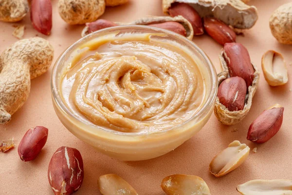 Schüssel Erdnussbutter Und Erdnüsse Drumherum Auf Beigem Hintergrund — Stockfoto