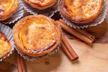 Pastel de nata turtaları ve ahşap tepside tarçın çubukları. Üst görünüm.
