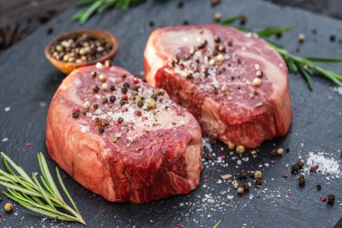 Gri tahtada tuzlu ve otlu çiğ pirzola bifteği. Üst görünüm.