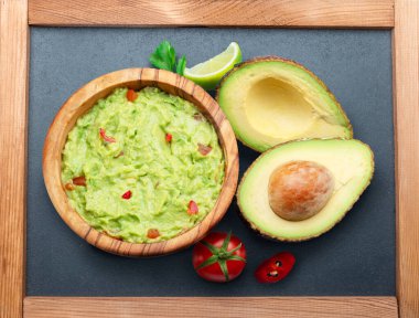 Avokado meyvesinin guacamole ve enine kesitleri gri tahta üzerinde. Üst görünüm.