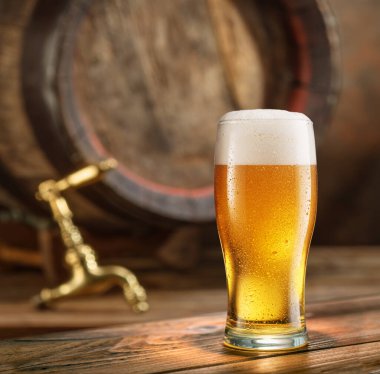 Arka planda bir bardak soğuk bira ve ahşap bira fıçısı.. 