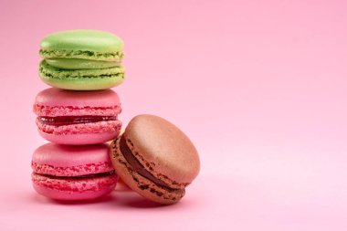 Colorful french macarons isolated on pink background.