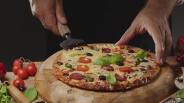 Şef pizza küreklerini bir dilim pizzayı kaldırmak için kullanır ve bu sırada da peyniri uzatır. Koyu arkaplanda geleneksel İtalyan yemekleri.