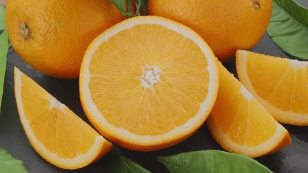 Reife Orangenfrüchte Mit Scheiben Und Orangenblättern Bewegen Sich Langsam Rahmen — Stockvideo