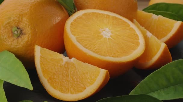 スライスしたオレンジの果実とオレンジの木の葉をゆっくりと灰色の石のテーブルの上に移動します あなたのプロジェクトのための素晴らしいフルーツの背景 マクロビデオシューティング — ストック動画