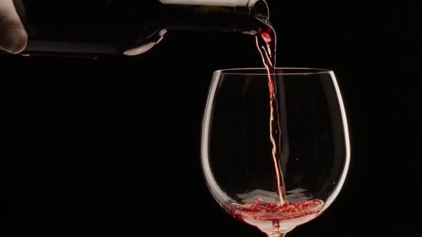赤ワインは黒い背景にガラスに注がれています スローモーション クローズショット あなたのプロジェクトのための素晴らしいワインの背景 — ストック動画