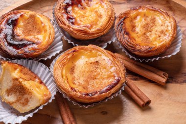 Pastel de nata turtaları ve ahşap tepside tarçın çubukları. Üst görünüm.