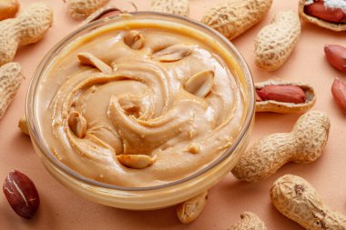 Bej arka planda bir kase fıstık ezmesi ve fıstık. Üst görünüm.