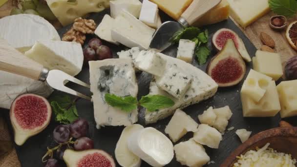 フルーツ ミント ナッツ チーズ切断ナイフのスライスチーズのバリエーションはフレーム内でゆっくり回転します あなたのプロジェクトのための素晴らしいチーズの背景 — ストック動画