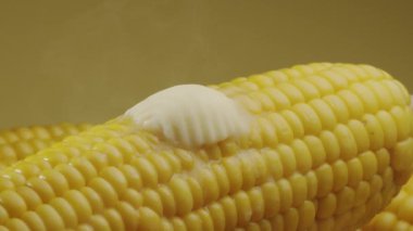 Bir parça tereyağı olgun haşlanmış mısır koçanı boyunca yavaşça hareket eder. Projelerin için güzel bir yemek geçmişi var. Makro video çekimi. 