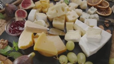 Meyveli, naneli, fındıklı ve peynirli dilimlenmiş peynirlerin çeşitliliği çerçevede yavaşça döner. Projeleriniz için harika bir peynir arka planı..