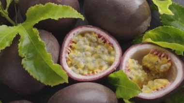 Tutku meyveleri, tutku meyveleri ve tutku meyveleri içeren olgun meyveler gri bir taş masanın üzerindeki çerçevede yavaşça hareket eder. Projelerin için egzotik meyve arkaplanı. Makro video çekimi.