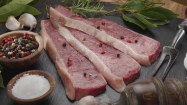 Gri bir tezgahın üzerinde baharat ve otlarla dilimlenmiş üç parça picanha bifteği yavaşça çerçevede döner. Geleneksel Portekiz yemekleri.