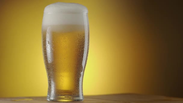 Glas Bier Draait Langzaam Een Gele Achtergrond Condensatie Het Bierglas — Stockvideo