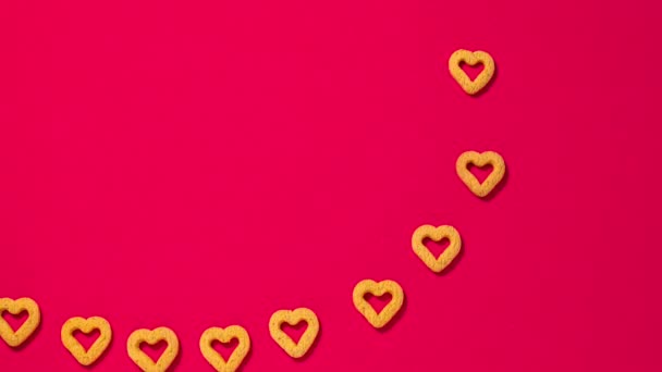 アニメーション漫画のビデオ 赤い背景の小さなハート型のクッキーは 大きな心臓にラインアップし フレームから出て行きます バレンタインデーのための美しい面白いビデオ — ストック動画