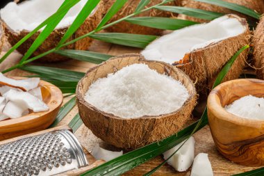 Tahta bir masada hindistan cevizi dilimleri, gevrek ve hindistan cevizi yapraklarıyla birlikte taze açılmış hindistan cevizleri. Projeleriniz için güzel meyve arkaplanı. 