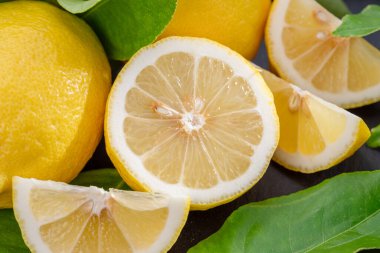 Gri taş bir masada dilimler ve limon yapraklarıyla olgun limon meyveleri. Projeleriniz için güzel meyve arkaplanı.. 
