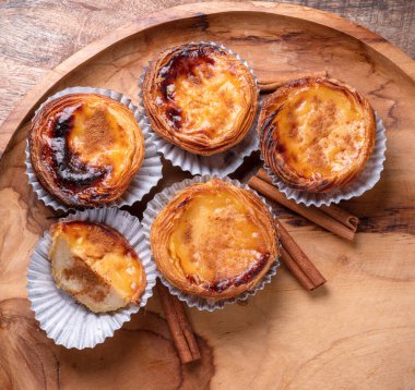 Pastel de nata turtaları ve ahşap tepside tarçın çubukları. Üst görünüm.