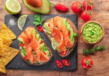 Somon tostları - somon dilimleri ve avokado soslu ekmek, guacamole ve tortilla cipsi. Üst görünüm.