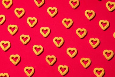 Kırmızı arka planda küçük kalp şeklinde kurabiyeler. Sevgililer Günü için güzel bir geçmiş..