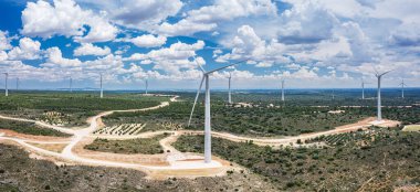 Kırsal alanda rüzgar türbinleri ve arka planda çarpıcı bulutlu gökyüzü. Çevre dostu elektrik enerjisi üretimi.