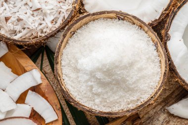 Tahta bir masada hindistan cevizi dilimleri, gevrek ve hindistan cevizi yapraklarıyla birlikte taze açılmış hindistan cevizleri. Projeleriniz için güzel meyve arkaplanı. 