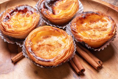 Pastel de nata turtaları ve ahşap tepside tarçın çubukları. Üst görünüm.