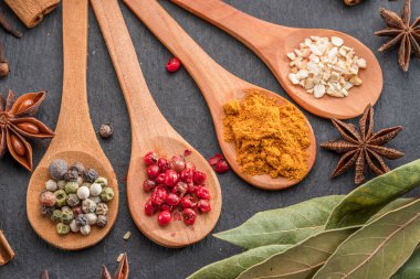 Gri taş masadaki tahta kaşıklarda çeşitli baharatlar, projeleriniz için harika yemek arkaplanı..