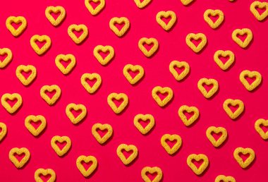 Kırmızı arka planda küçük kalp şeklinde kurabiyeler. Sevgililer Günü için güzel bir geçmiş..