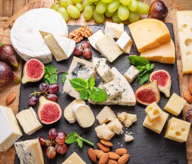 Meyve, nane, fındık ve peynir kesme bıçaklarıyla dilimlenmiş peynir çeşitleri. Projeleriniz için harika peynir arkaplanı.
