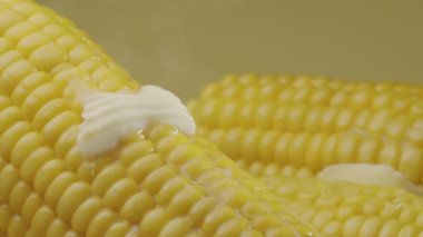 Bir parça tereyağı olgun haşlanmış mısır koçanı boyunca yavaşça hareket eder. Projelerin için güzel bir yemek geçmişi var. Makro video çekimi. 