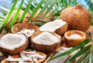 Tahta bir masada hindistan cevizi dilimleri, gevrek ve hindistan cevizi yapraklarıyla birlikte taze açılmış hindistan cevizleri. Projeleriniz için güzel meyve arkaplanı. 