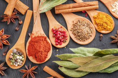 Gri taş masadaki tahta kaşıklarda çeşitli baharatlar, projeleriniz için harika yemek arkaplanı..