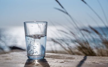 Plastik şişeden bardağa su dökmek. Doğa arkaplanı.