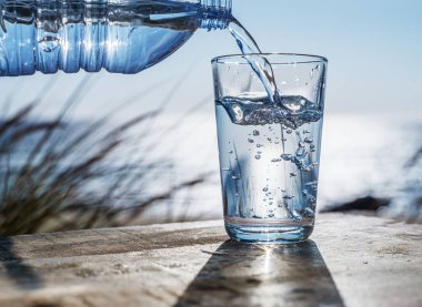 Plastik şişeden bardağa su dökmek. Doğa arkaplanı.