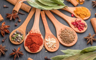 Gri taş masadaki tahta kaşıklarda çeşitli baharatlar, projeleriniz için harika yemek arkaplanı..