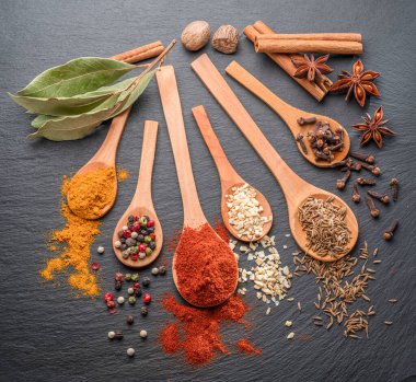 Gri taş masadaki tahta kaşıklarda çeşitli baharatlar, projeleriniz için harika yemek arkaplanı..