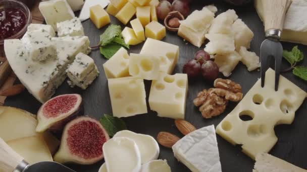 Verschiedene Käsesorten Mit Früchten Minze Nüssen Und Käseschneidemessern Rotieren Langsam — Stockvideo