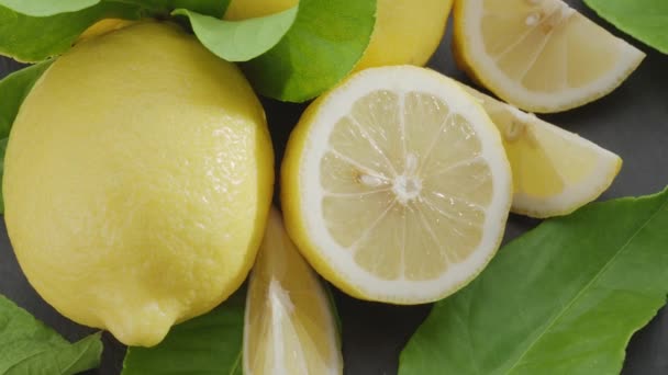 スライスしたレモンの果実とレモンの葉を灰色の石のテーブルの上にゆっくりと動かします あなたのプロジェクトのための素晴らしいフルーツの背景 マクロビデオシューティング — ストック動画
