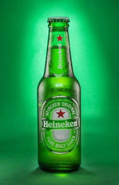 Portekiz, Lizbon, 9 Aralık 2023: Bir şişe Heineken birası 0.33l ve yeşil arka planda izole edilmiş damlalar. Heineken, dünyanın en popüler bira markalarından biridir..
